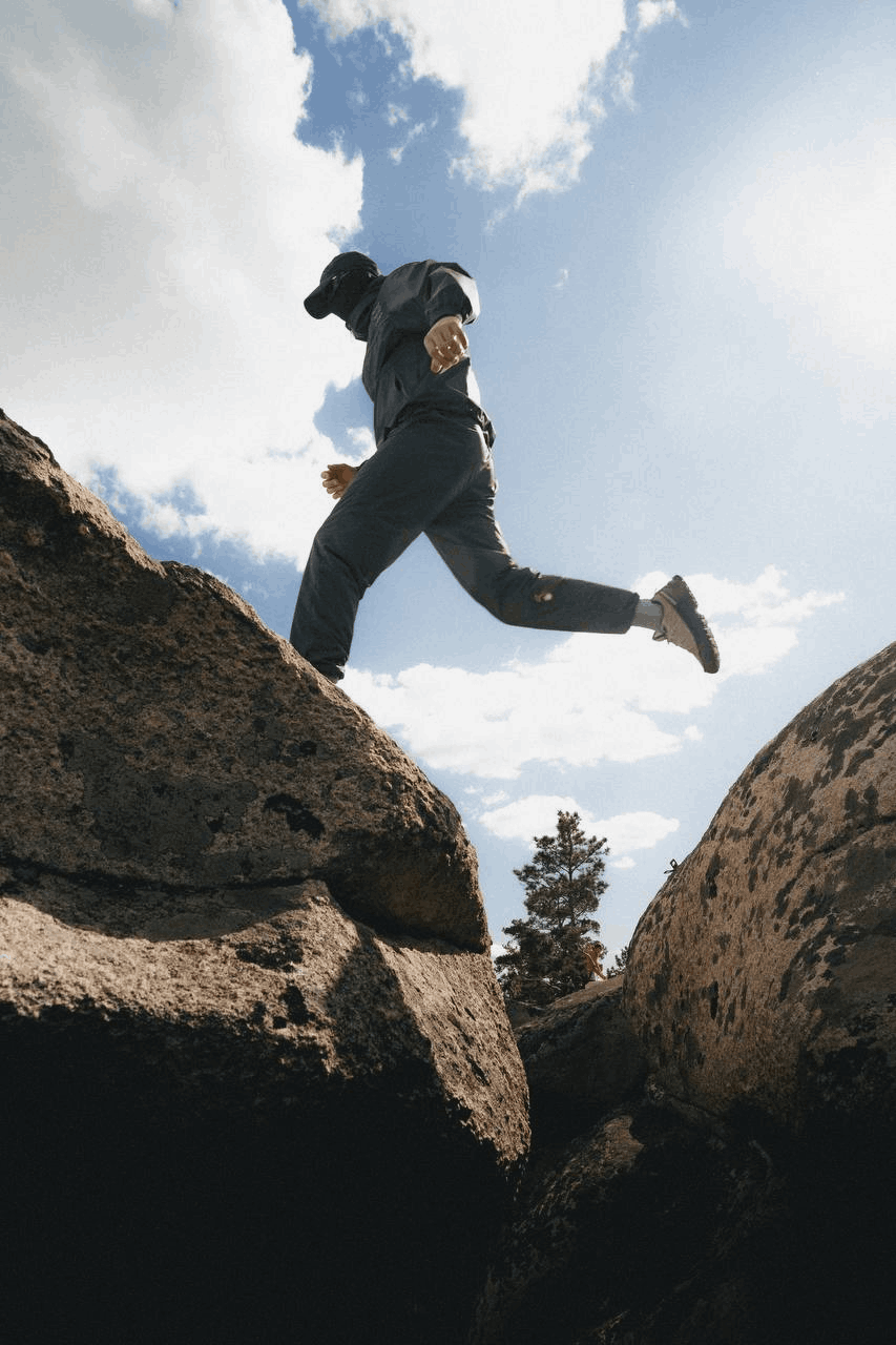 Изображение человека перепрыгивающего с камня на камень в фирменной одежде НЕАЛИТ